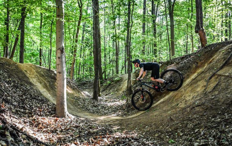 person riding bike through dip on trail